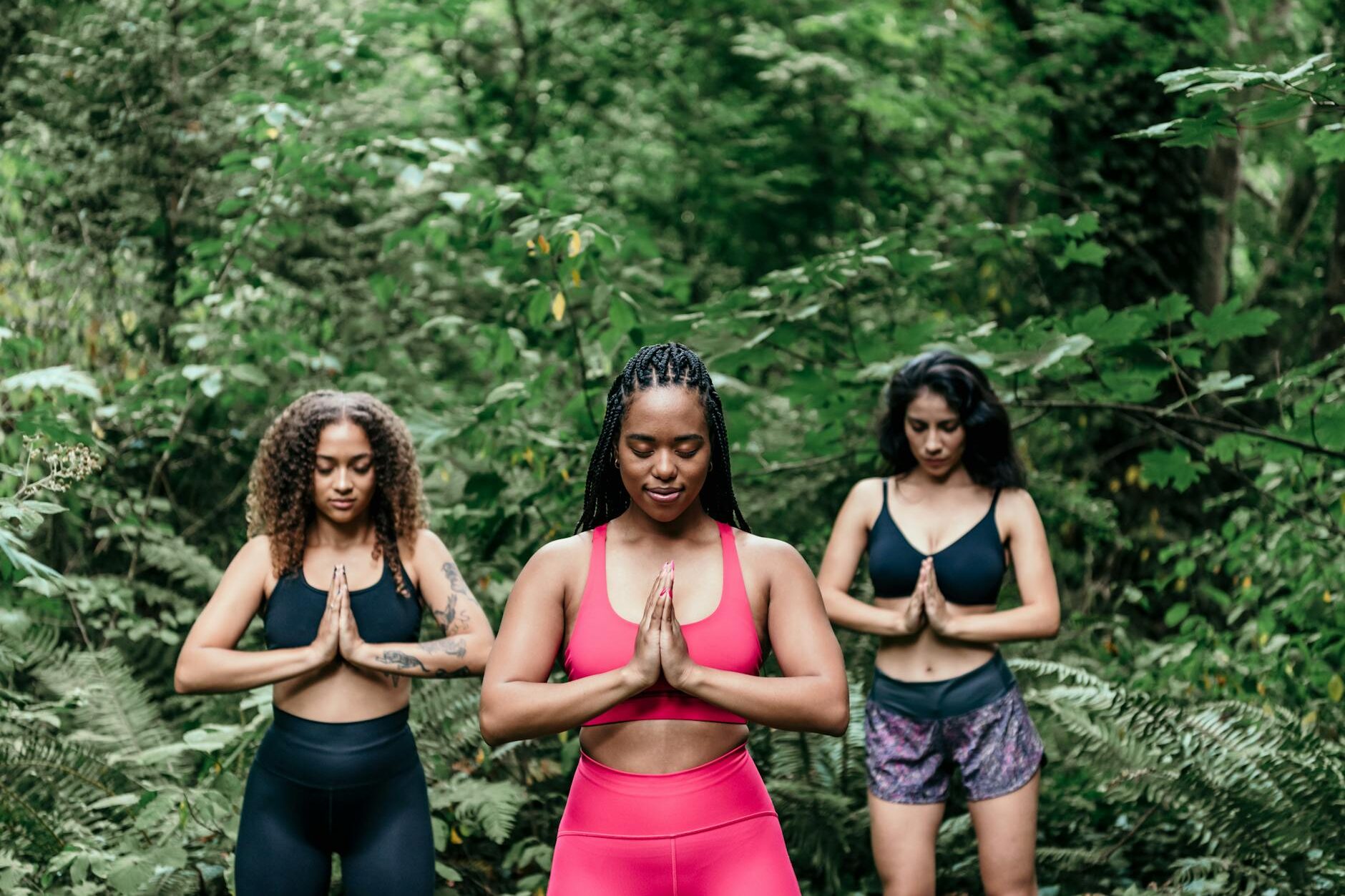 women wearing sports bra meditating in the woods