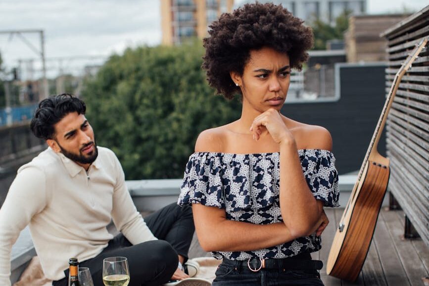 man in white long sleeve shirt sitting beside woman in black and white floral dress